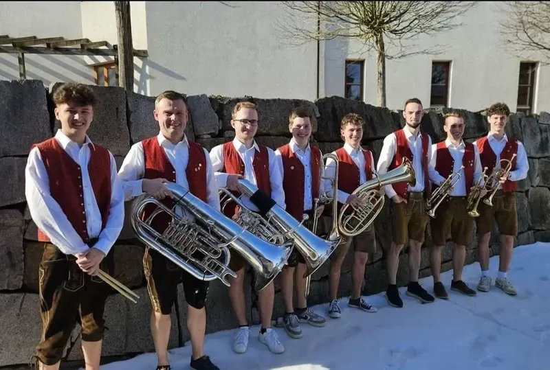 Die WindBradler mit ihren Instrumenten vor einer Steinmauer im Schnee